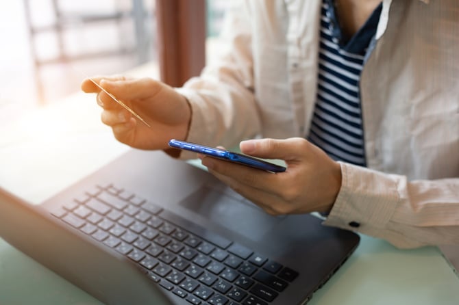 Empreendedor com notebook aberto e celular na mão realizando venda com Link de Pagamento Mercado Pago