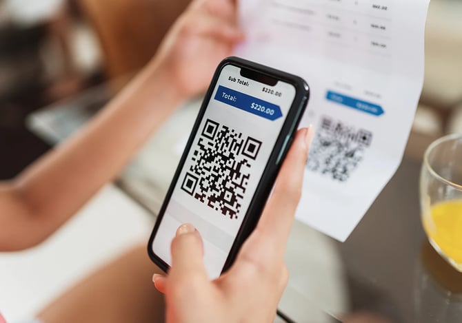 Pessoa escaneando o Código QR e Pix de uma conta com o celular