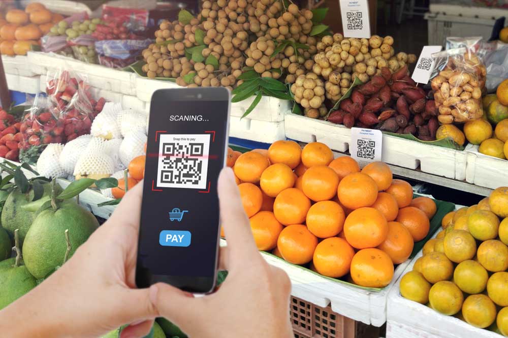 Um celular escaneando um QR Code em uma barraca de frutas. 