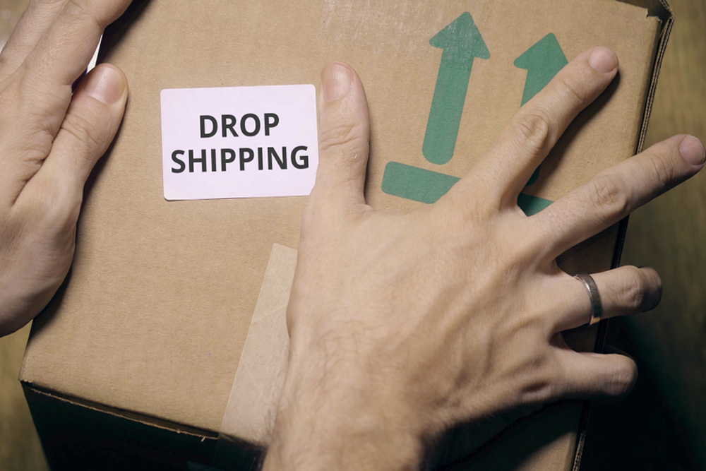 Uma mão segurando uma caixa com a palavra “dropshipping” escrita em cima.