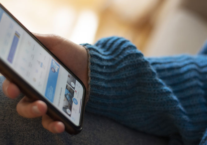 Mão de uma pessoa vestindo um suéter azul segurando um smartphone com a tela aberta na conta do Banco Digital Mercado Pago