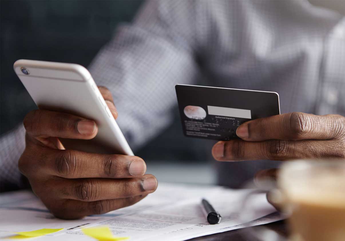 Homem mexendo no celular enquanto analisa o cartão de benefícios